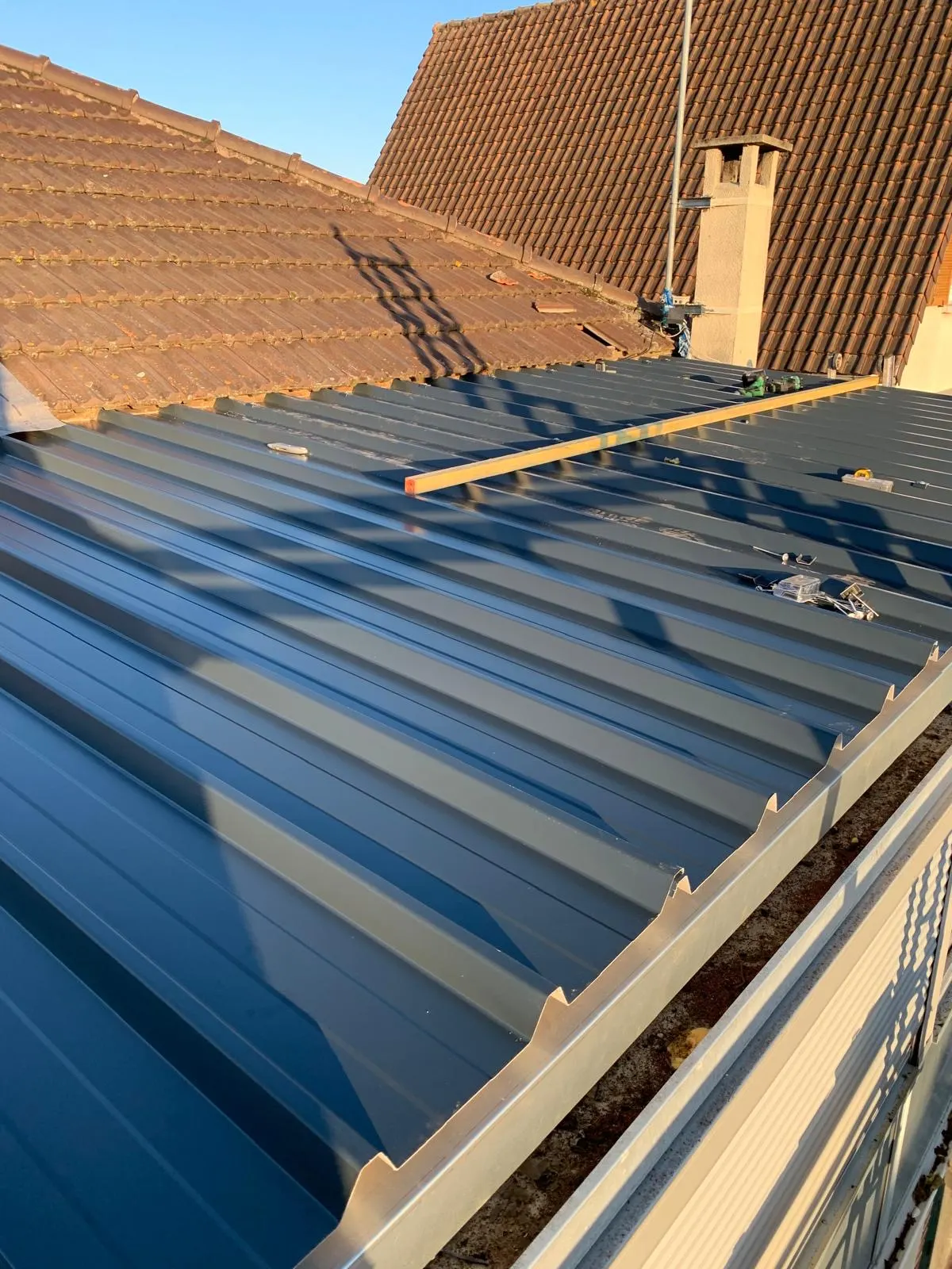 Raccord entre une couverture bac acier neuve et une toiture en tuiles existante, chantier de notre équipe en Île-de-France