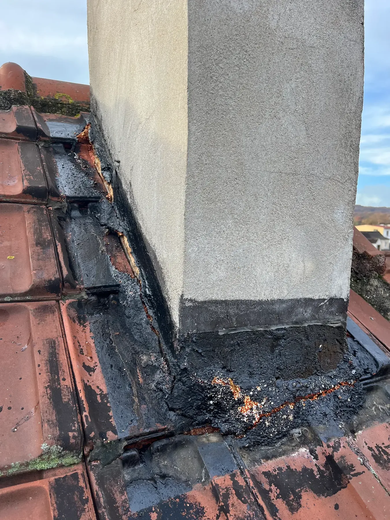 Entourage de cheminée avant travaux avec ancienne étanchéité dégradée sur toiture en tuiles